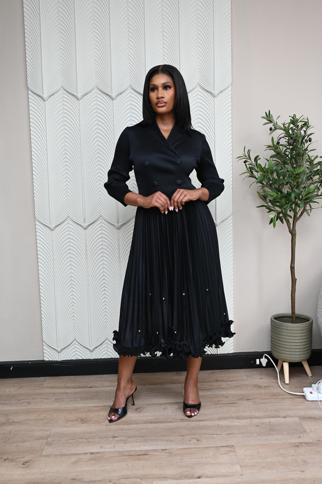 The Executive Muse Dress in black, full-length front view with double-breasted blazer bodice and pleated pearl-trim skirt